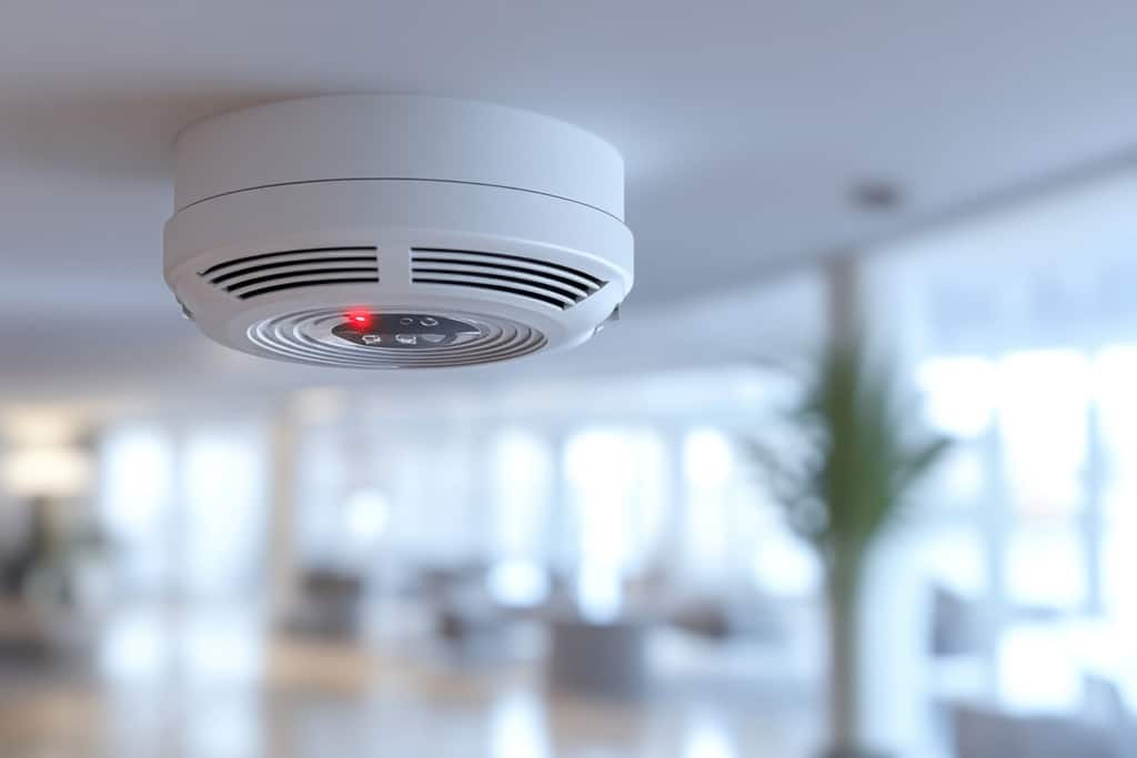 Fire alarm. A smoke detector mounted on a ceiling, featuring a r